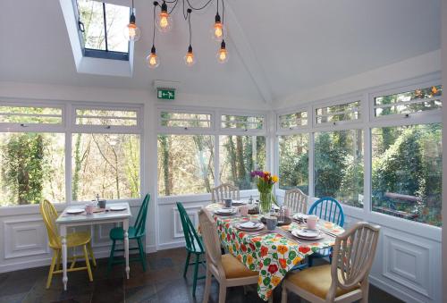 a dining room with a table and chairs and windows at Summerhill Guest House in Betws-y-coed