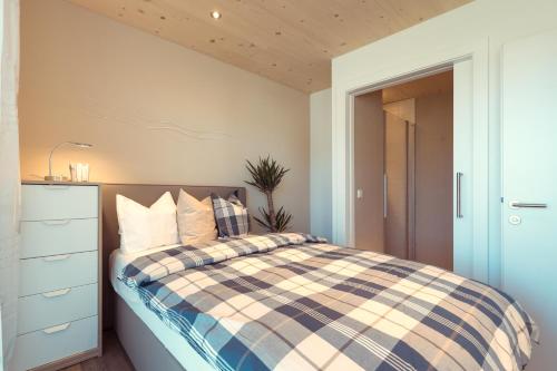 a bedroom with a bed with a checkered blanket at Simply Home Apartments in Ueberackern