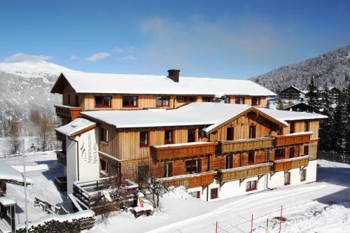 a large wooden building with snow on the ground at Appartementhaus Speckalm in Katschberghöhe