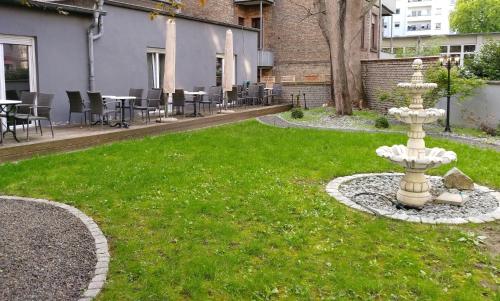 a fountain in the middle of a lawn with tables and chairs at Wasserturm Hotel Mannheim in Mannheim