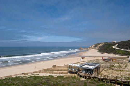 a view of a beach with a building and the ocean at Bungalows Land'shause in Pataias