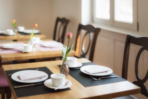 einen Holztisch mit Teller und Tassen und eine Vase mit Blumen in der Unterkunft Hotel Villa8 in Villingen-Schwenningen