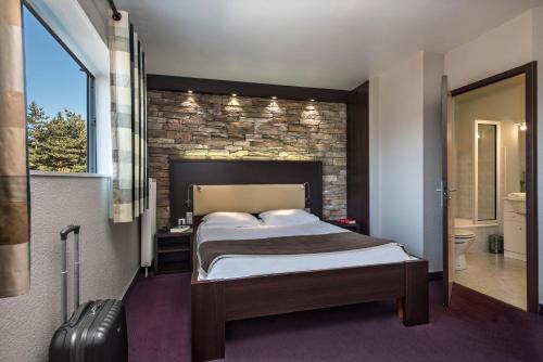 a bedroom with a bed and a stone wall at Les Portes d'Apcher in Saint-Chély-dʼApcher