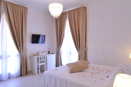 a white bedroom with a bed and a table and window at Villa Miriam in Gragnano
