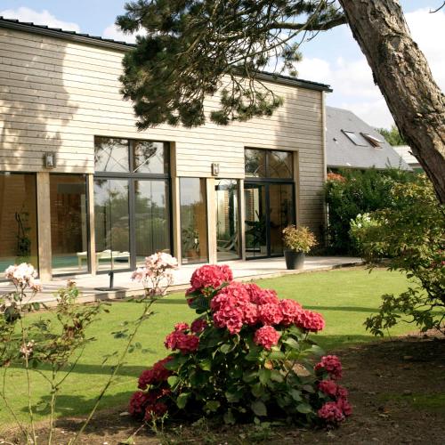 a house with red flowers in front of it at Nature et Lin in Néville