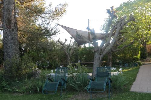 ユゼスにあるMas Myroの木の横に座る緑の椅子2脚