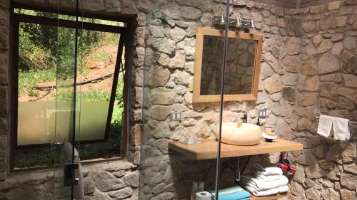a stone bathroom with a sink and a mirror at Cabañas Caballieri in Pisco Elqui