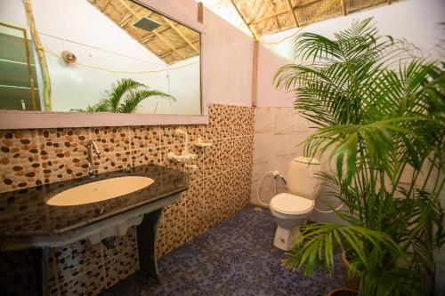 a bathroom with a sink and a toilet and a plant at Blue Lagoon Resort Goa in Cola