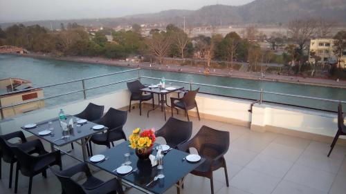 a restaurant with tables and chairs on a balcony at Ganga Exotica in Haridwār