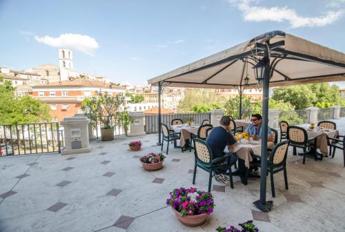 a patio area with tables, chairs and umbrellas at Hotel Iris in Perugia