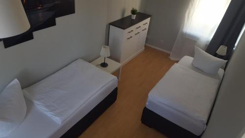 a small bedroom with two beds and a lamp at Pension Fischerjung in Rostock