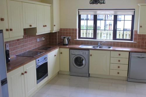 a kitchen with white cabinets and a washing machine at Lough Rynn House in Mohill
