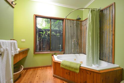 Un baño con bañera y ventana. en Crater Lakes Rainforest Cottages, en Yungaburra