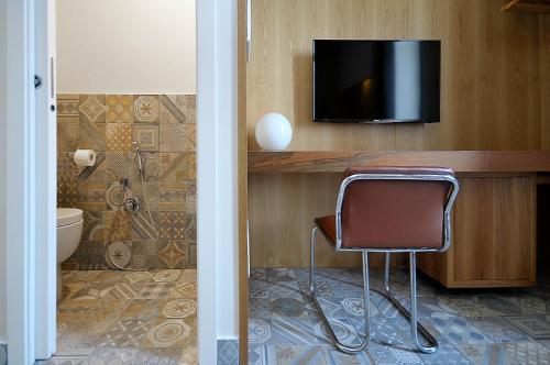 a bathroom with a chair and a television on a wall at Villa Battista in Ercolano