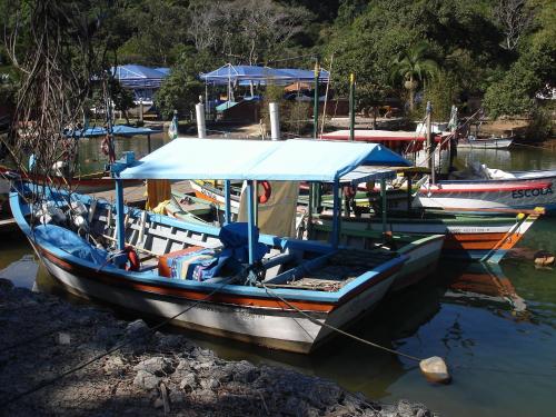 a boat with a blue canopy sitting in the water at Pousada Larimor in Boicucanga