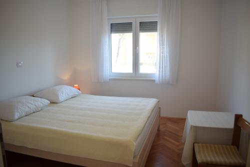 a white bedroom with a bed and a window at Apartment Mary in Porat