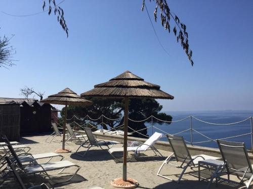 a group of chairs and umbrellas on a beach at Stella Maris Resort in Camogli