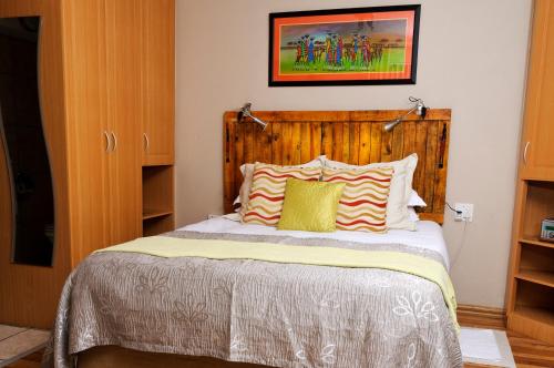 a bedroom with a bed with a wooden headboard at Country Park Guest House - Muldersdrift in Muldersdrift