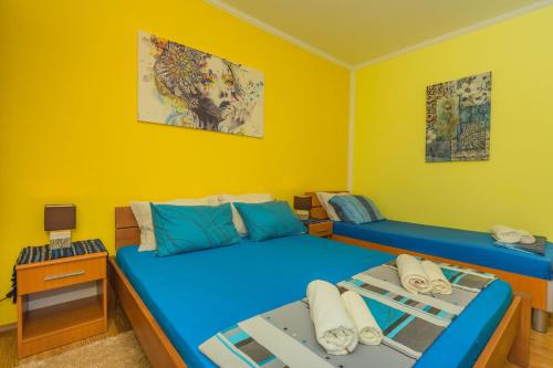 two beds in a room with yellow walls at Villa Nena Apartments Sutomore in Sutomore