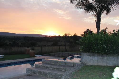 a swimming pool with a sunset in the background at Country Park Guest House - Muldersdrift in Muldersdrift