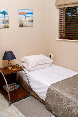 a bedroom with a bed and a table with a lamp at Country Park Guest House - Muldersdrift in Muldersdrift
