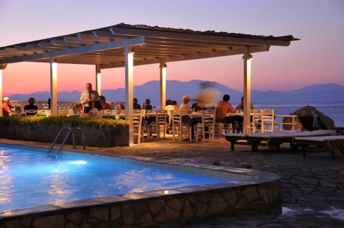 a group of people sitting at a table near a swimming pool at Lido Hotel in Xylokastron