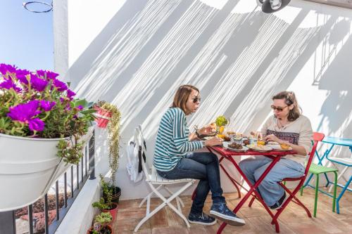 two women sitting at a table on a balcony eating food at Casas da Formosa - Casa do Postigo in Tavira