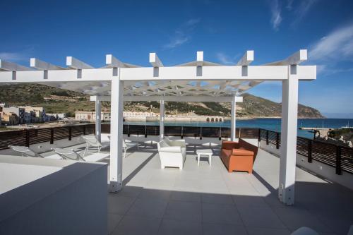 einen Pavillon mit Stühlen und Tischen am Strand in der Unterkunft Le Ancore Luxury Apartments in Favignana