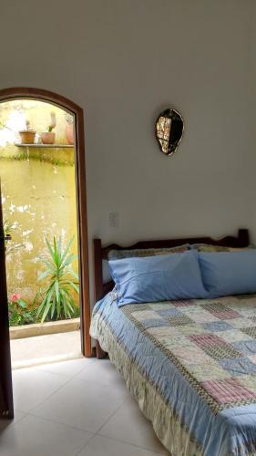 a bedroom with a bed and a view of a garden at Suíte no jardim - Praia dos Anjos in Arraial do Cabo