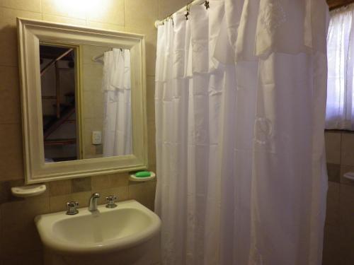 a bathroom with a sink and a white shower curtain at Cabañas La Curucucha in Nono