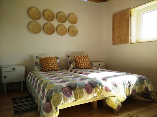 a bedroom with a bed and a window and plates on the wall at Taipa 2 - Casas de Campo do Junqueirinho in Bicos