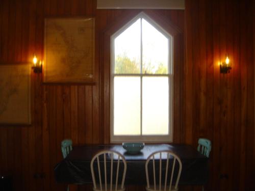 a dining room table with two chairs and a window at St Andrews Church Nave in Ophir