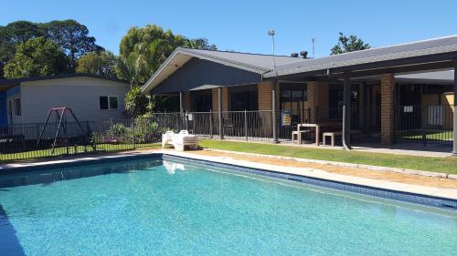 a swimming pool in front of a house at Colonial Tweed Holiday & Home Park in Tweed Heads