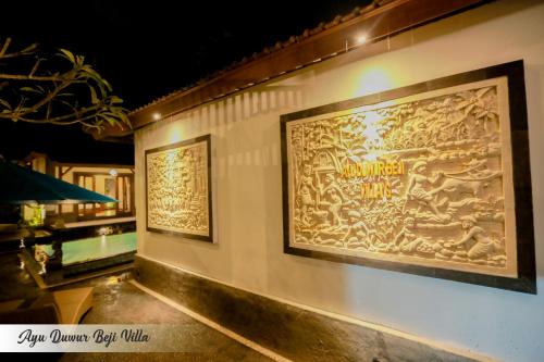 a wall with two large paintings on it at Ayu Duwur Beji in Ubud