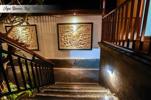 a set of stairs with two paintings on the wall at Ayu Duwur Beji in Ubud