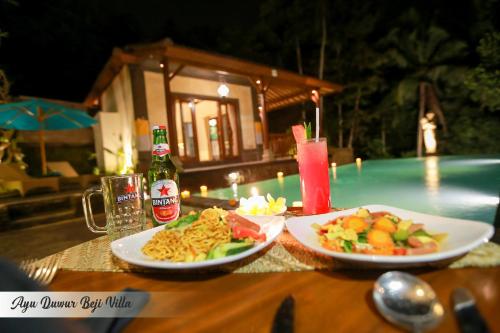 a table with two plates of food and a drink at Ayu Duwur Beji in Ubud