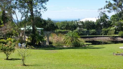 a yard with green grass and trees and a bridge at Hilltop Hideaway in Ninderry