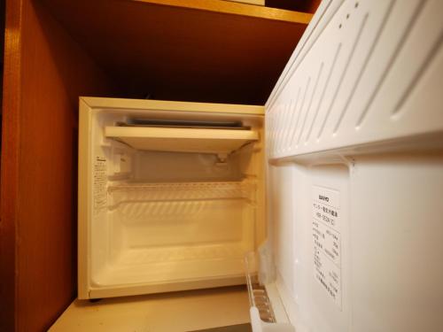 a white refrigerator freezer sitting inside of a kitchen at Hotel Route-Inn Mojiko in Kitakyushu