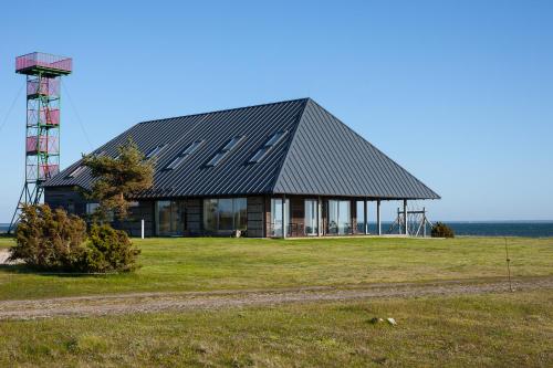 a house on a field next to the ocean at Harbor House Lõmala in Lõmala