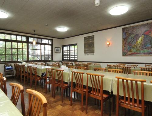 una sala da pranzo con tavoli e sedie bianchi di Yokokura Ryokan a Nagano