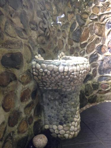 a bathroom with a stone toilet in a stone wall at Kupu Kupu Garden Guest House & Cafe in Bukit Lawang