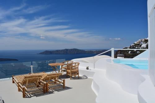 a balcony with a table and chairs and the ocean at Cocoon Suites in Imerovigli