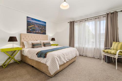 a bedroom with a bed and a chair and a window at Blue Rosella on Piper in Kyneton
