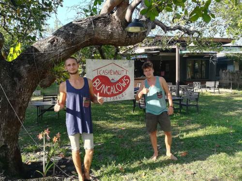 two people standing under a tree with a cocacola sign at Cashew Nut Bungalow, Ko Mook in Koh Mook
