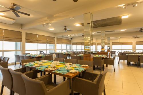 a dining room with tables and chairs and windows at Hotel Topaz in Kandy