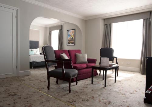 a living room with a red couch and chairs at Royal Victoria Hotel in Hastings