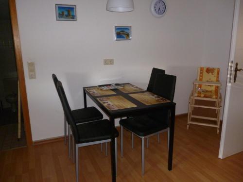 a dining room table with chairs and a clock on the wall at Fa Haack in Neuried