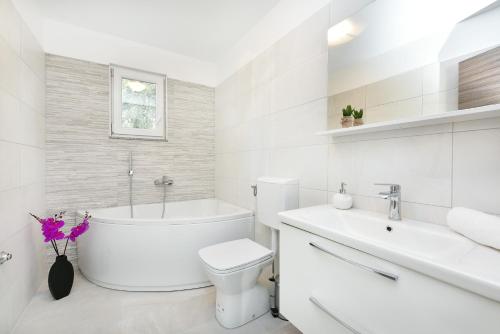 ein weißes Badezimmer mit einer Badewanne, einem WC und einem Waschbecken in der Unterkunft Apartman Kresan in Sukošan