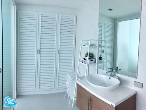 une salle de bain blanche avec un lavabo et un miroir dans l'établissement My Resort Hua Hin by Skystar, à Hua Hin
