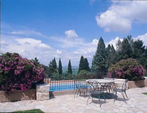 a patio with a table and chairs and flowers at Villa Luisa in Todi